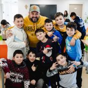 Een medewerker met een groep jongens die om hem heen dringen in het dagcentrum