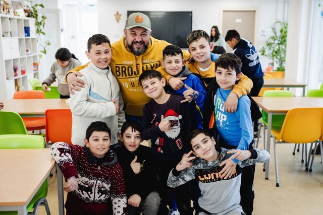 Een medewerker omringd door een groep lachende jongens in het dagcentrum